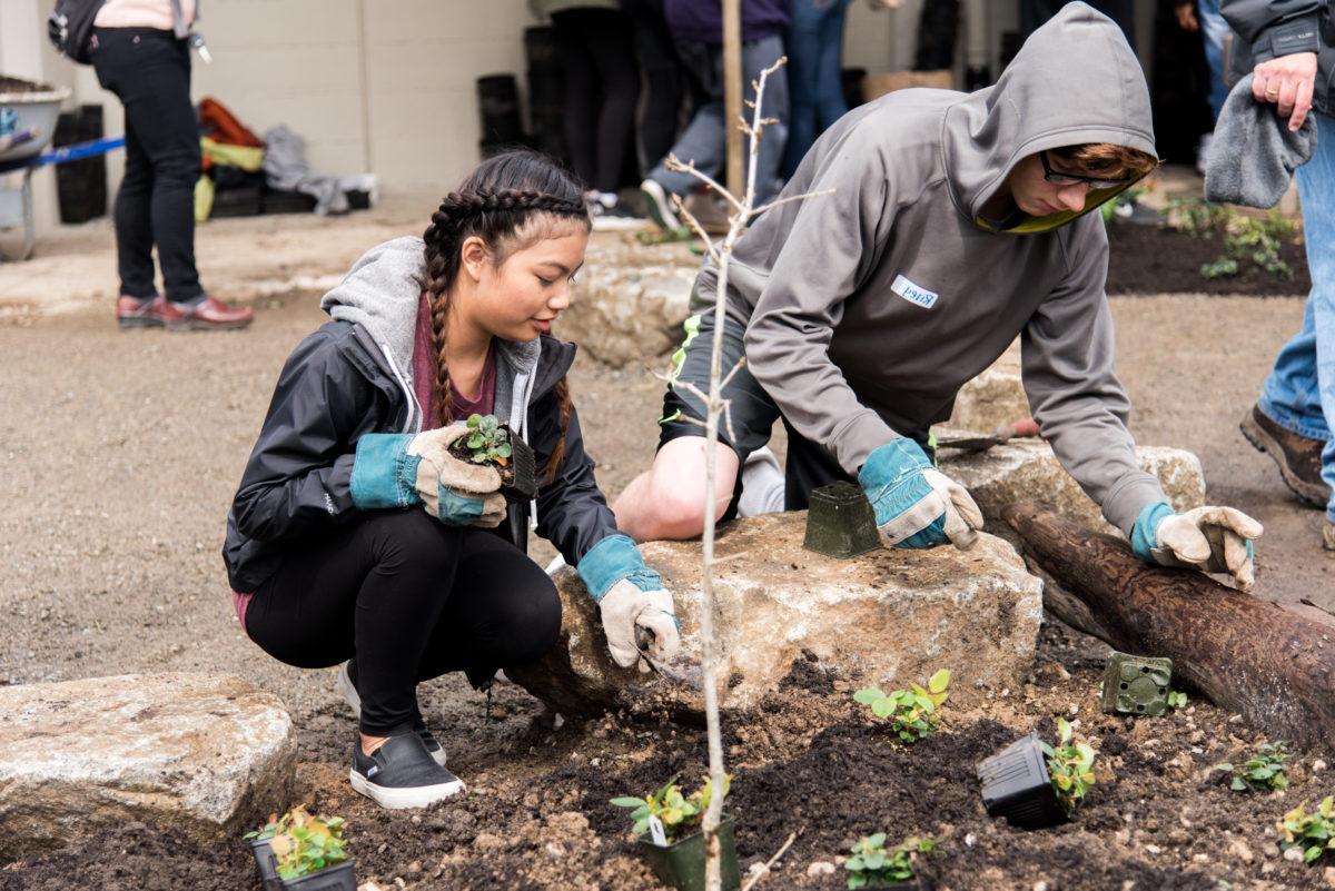 2 students wearing gloves planting in Sylvester Middle School's new rain garden