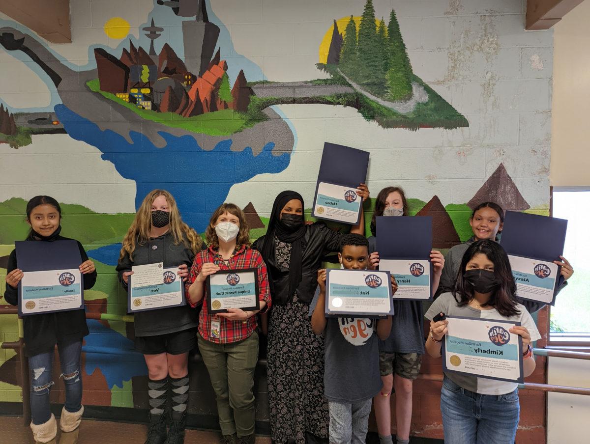 A group of students from Chinook Middle School's Unique Forest Club hold up their certificates after being honored as EarthGen Medalists.